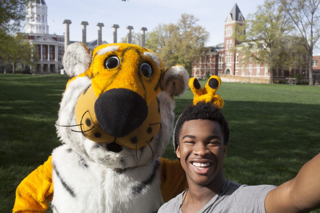 Truman the tiger playfully poses with a student in front of the columns at Mizzou.